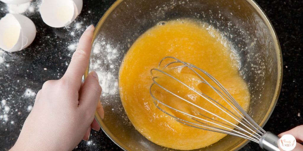 Whisking wet ingredients like eggs, pumpkin puree, and maple syrup for gluten-free bread batter