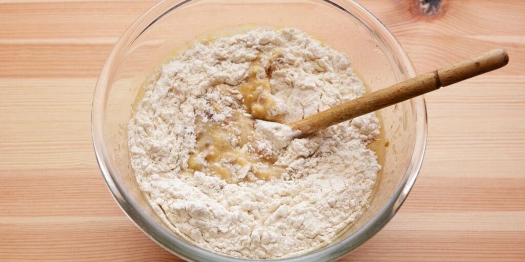 Mixing the batter for 4-ingredient banana bread, combining mashed bananas, eggs, flour, and baking powder