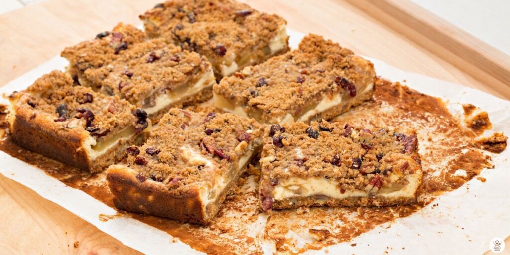 Sprinkling oat crumble topping on layered caramel apple cheesecake bars