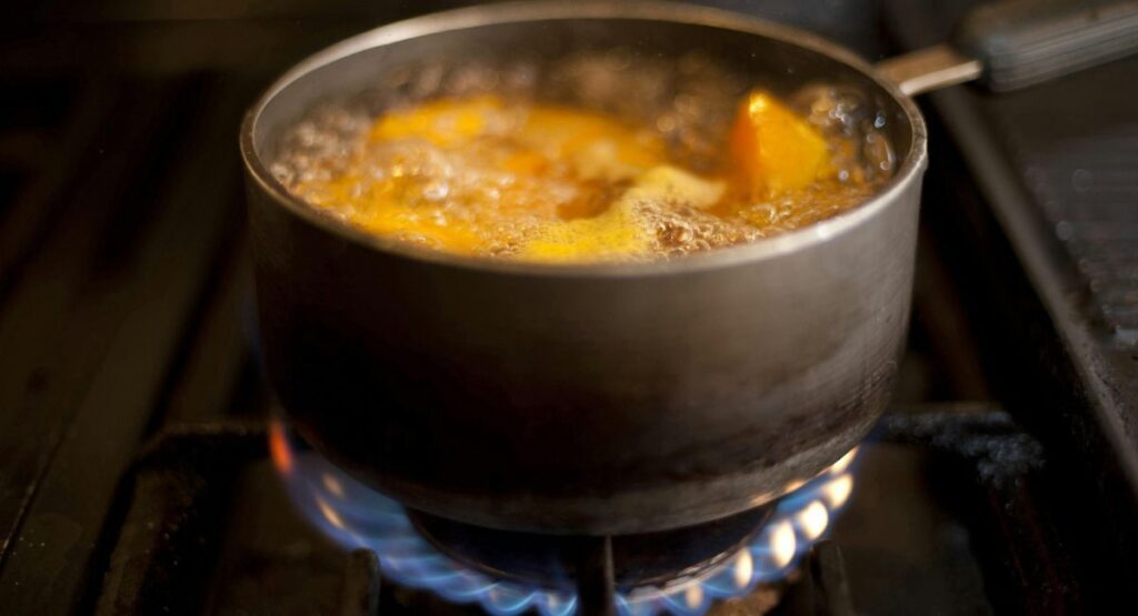 Apples boiling in pot with cinnamon and spices for applesauce recipe