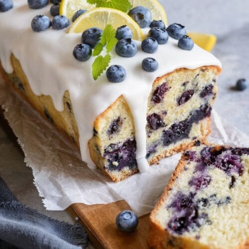 Freshly baked lemon blueberry bread loaf on a white plate