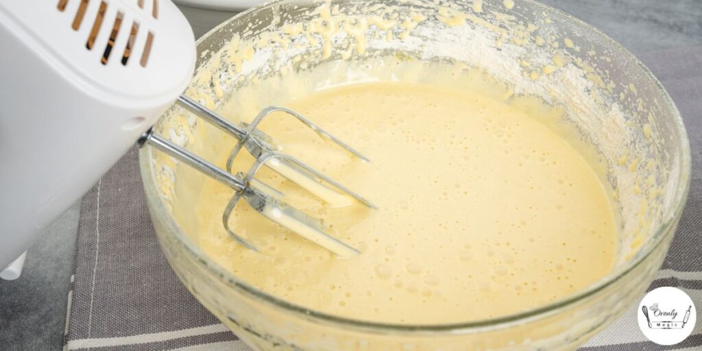 Cake batter being mixed in a large bowl with a hand mixer.