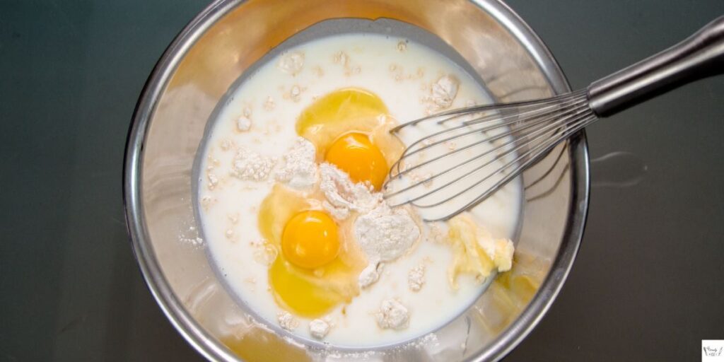 Ingredients for strawberry honey bun cake being mixed in a large bowl, including cake mix, sour cream, oil, and eggs.