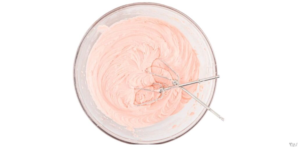 Mixing strawberry cake batter in a bowl for the honey bun cake recipe.