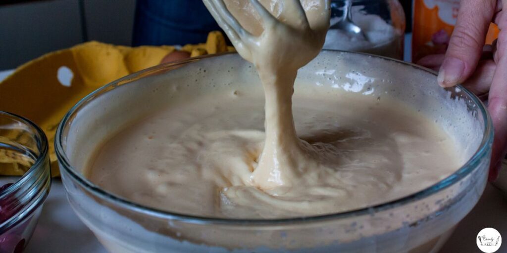 All-purpose flour being added into a wet mixture in a mixing bowl.
