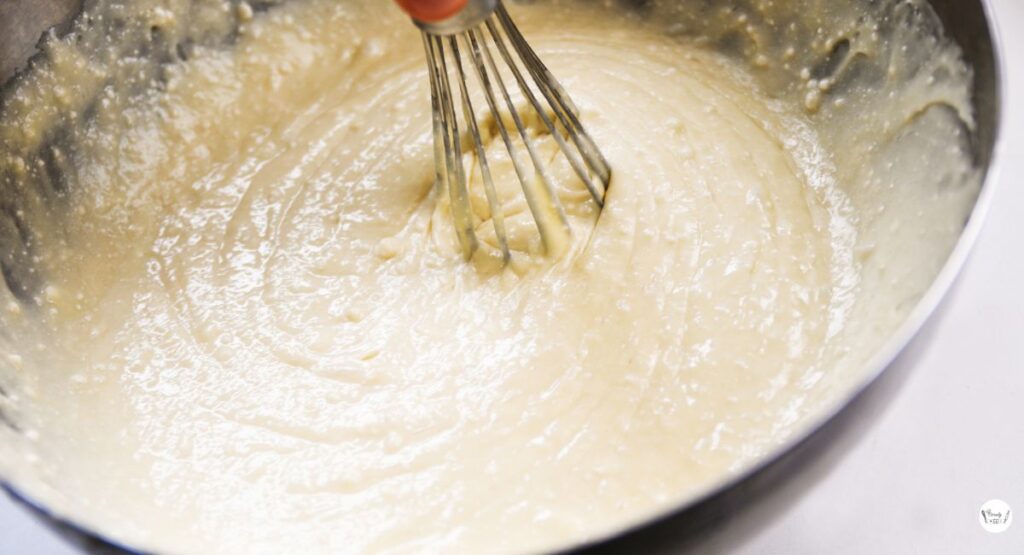 Mixing white cake mix, eggs, oil, and milk to prepare the batter for strawberry cream cheese earthquake cake.