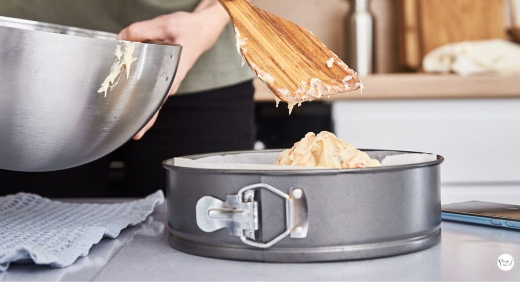 Cake batter being poured into a greased pan to make a homemade strawberry earthquake cake with cream cheese.