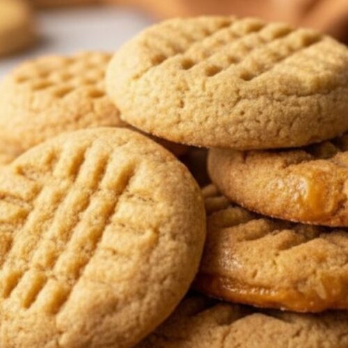 Soft eggless peanut butter cookies stacked on a plate with warm golden lighting