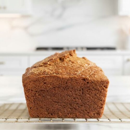 Freshly baked applesauce bread cooling on a wire rack with applesauce on the side.
