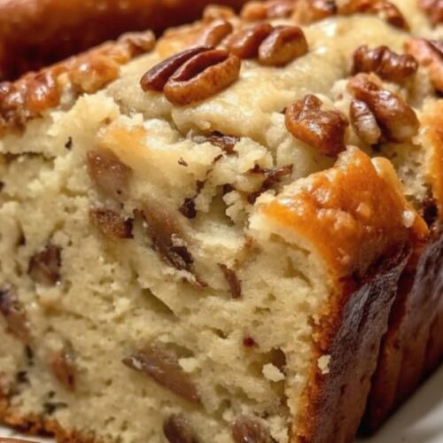 Sweet Alabama Pecan Bread loaf on a cooling rack, golden brown and topped with chopped pecans