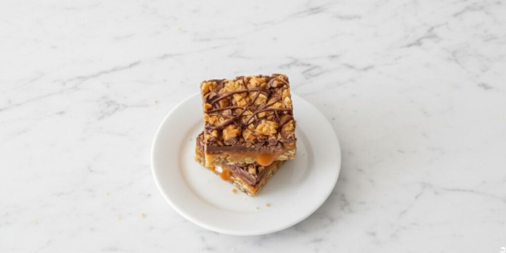 A single Caramel Chocolate Crunch Bar on a plate, showing the layers of crust, caramel, and chocolate