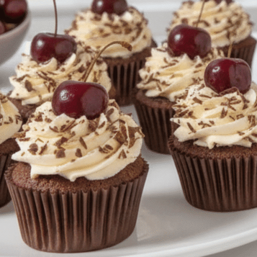 Plate of Black Forest Cupcakes with cherry filling cut open, showing moist chocolate sponge and whipped cream
