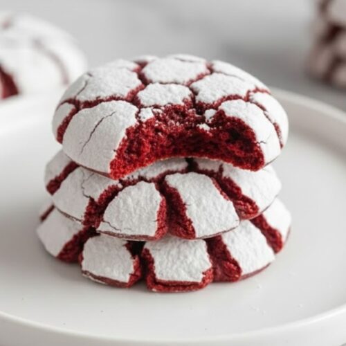 Freshly baked Red Velvet Crinkle Cookies rolled in powdered sugar on a cooling rack