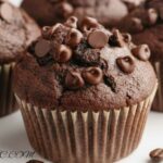 Freshly baked double chocolate espresso muffins topped with chocolate chips on a wooden tray.