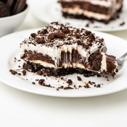 Whipped cream layer spread over chocolate pudding in a no-bake Oreo dessert