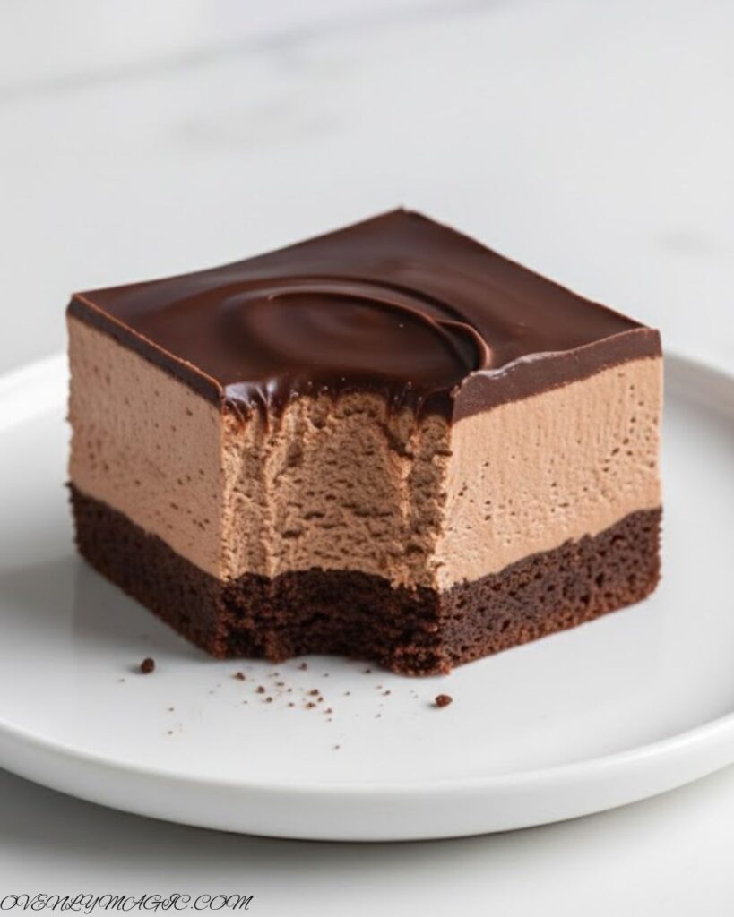 Chocolate mousse brownie squares served on a white plate with a fork