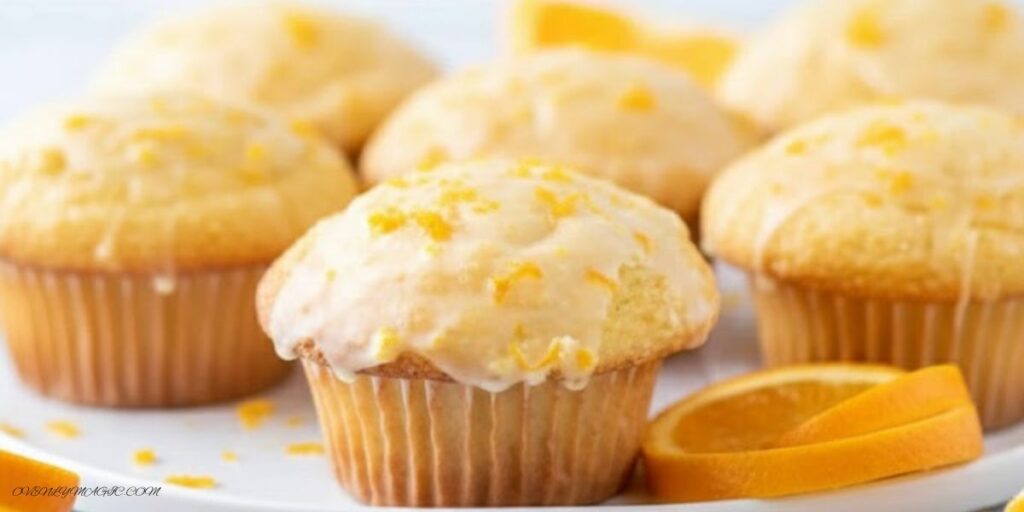Freshly baked Orange Muffins on a plate or wooden board, golden brown with orange zest sprinkled on top.