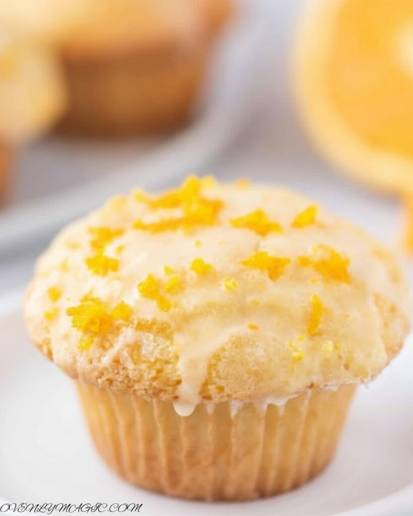 Freshly baked Orange Muffins on a plate or wooden board, golden brown with orange zest sprinkled on top.