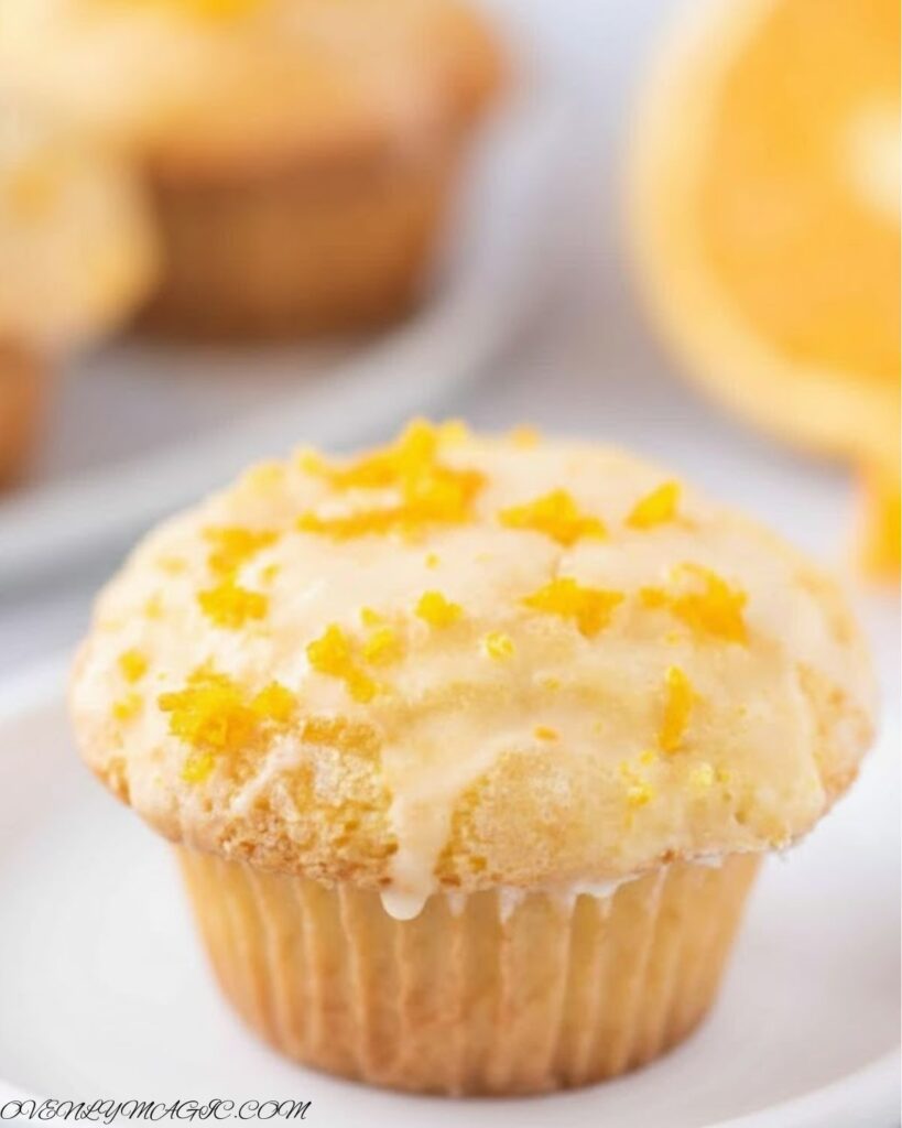 Freshly baked Orange Muffins on a plate or wooden board, golden brown with orange zest sprinkled on top.