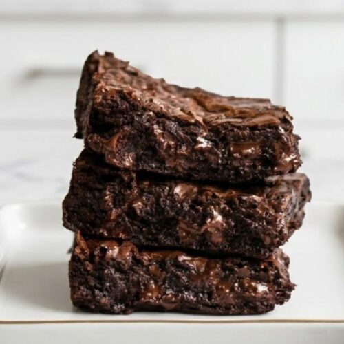 Fudgy Brown Butter Brownies with a shiny, crinkly top, melty chocolate chips, and rich nutty flavor, cut into squares on a parchment-lined pan