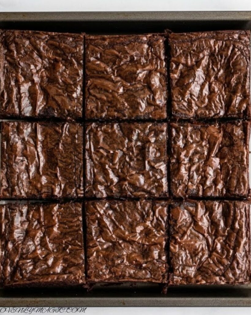 Fudgy Brown Butter Brownies with a shiny, crinkly top, melty chocolate chips, and rich nutty flavor, cut into squares on a parchment-lined pan